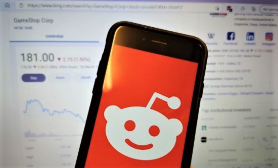 Phone with Reddit logo in front of GameStop stock prices