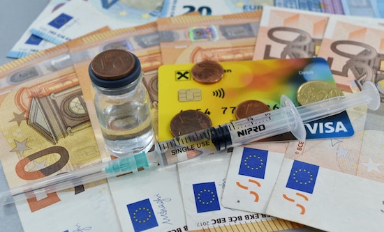 Medicine and syringe on Euro notes and coins