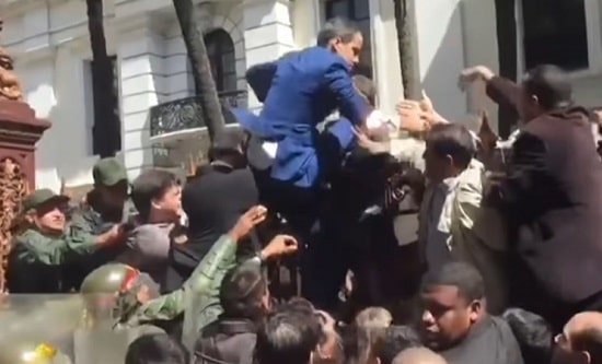 Juan Guaido attempts to climb over a fence as a stunt