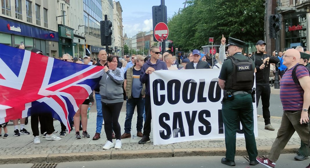 A Loyalist anti-immigration protest in Belfast with large British flag in 2024 supported by Dublin-based racists who carry a banner reading 'Coolock says no' (photo: Barry Duck Rodgers/Twitter)